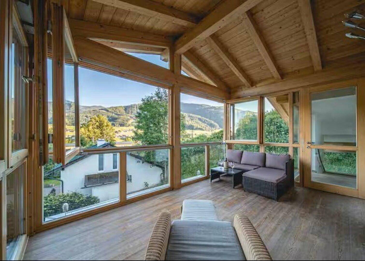 Gemütlicher Wintergarten mit Holzboden und Panoramablick auf die umliegende Landschaft.