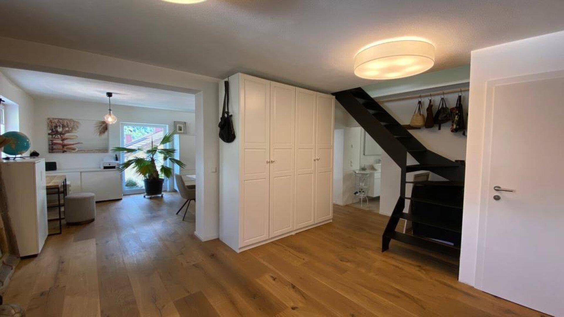 Offener Flurbereich mit Einbauschränken, Treppe und Übergang zum Wohn-Essbereich.