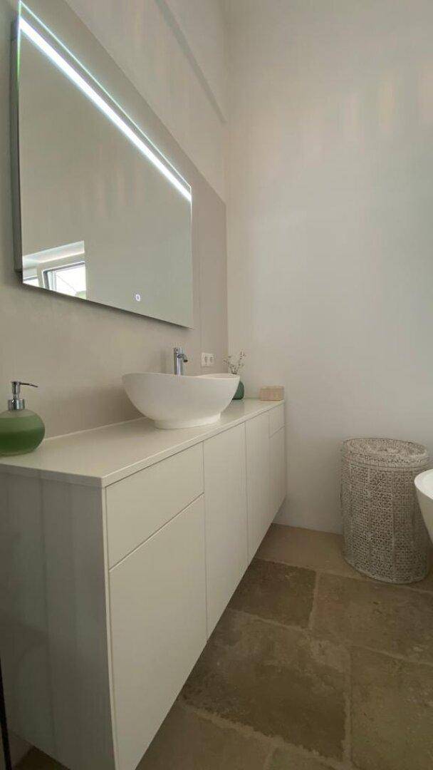 Modernes Badezimmer mit weißem Waschtisch, Aufsatzwaschbecken und großem Spiegel.