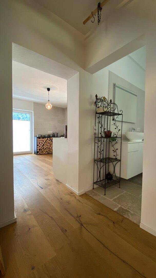 Heller Flur mit Holzboden, der zur Küche und zum Badezimmer führt.