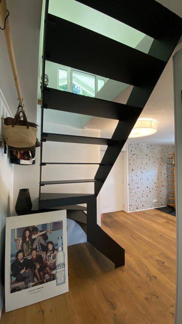 Moderne schwarze Treppe mit Holzboden und dekorativer Wandgestaltung im Flur.