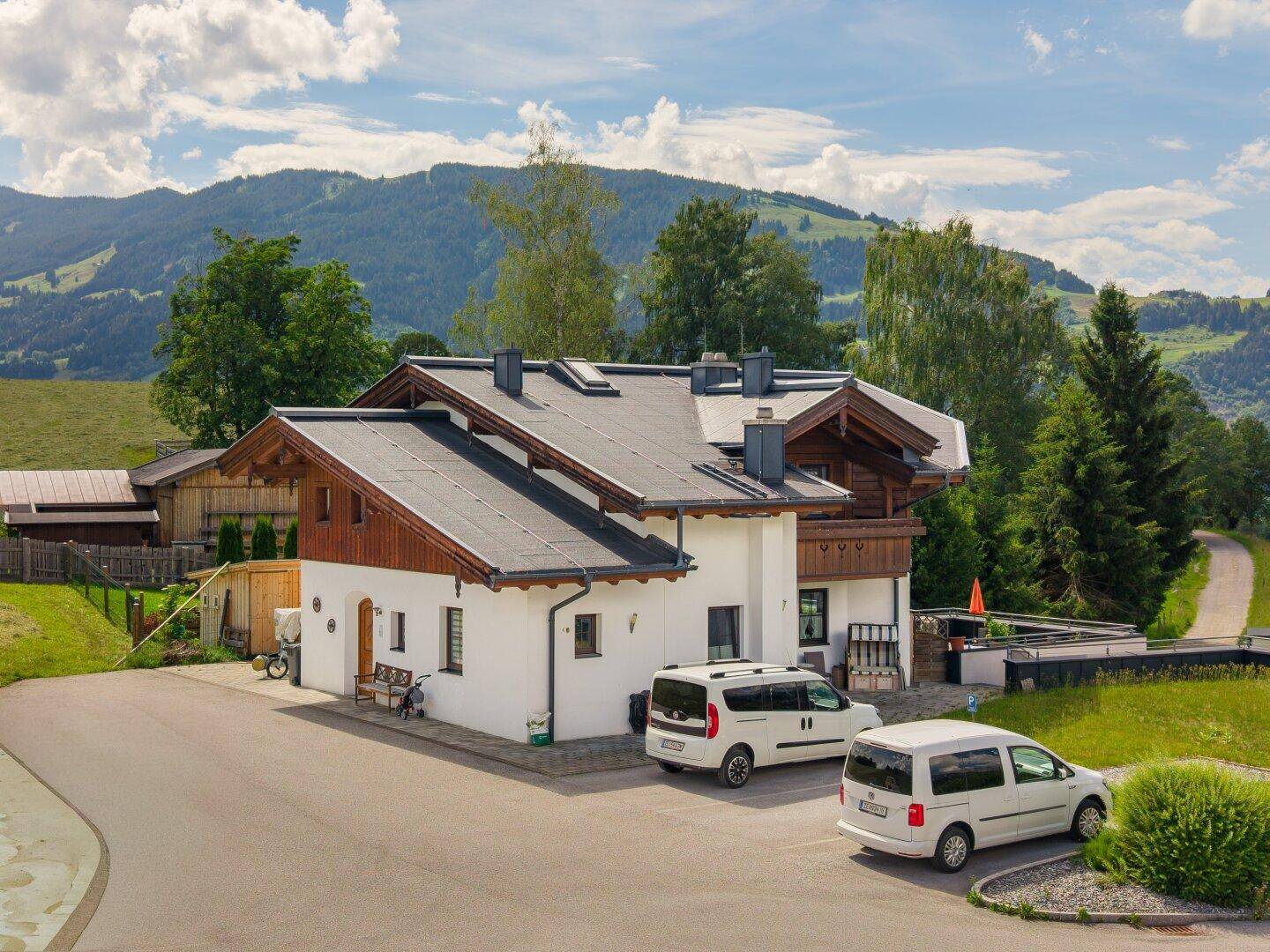 Alpines Gebäude mit Parkplätzen und Blick auf die sanften Hügel der Umgebung.
