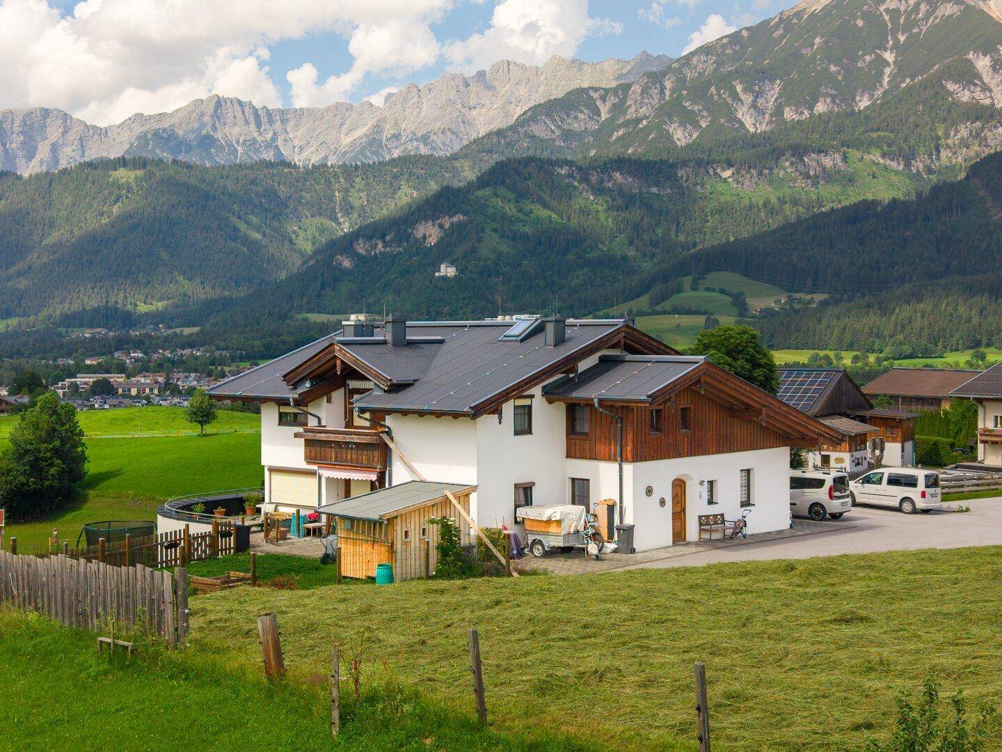 Weißes Gebäude mit Holzelementen, Gartenbereich und Bergblick in ländlicher Umgebung.