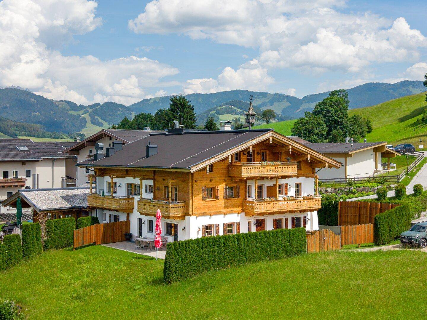 Traditionelles Chalet mit Holzbalkonen und gepflegtem Gartenbereich in den Bergen.