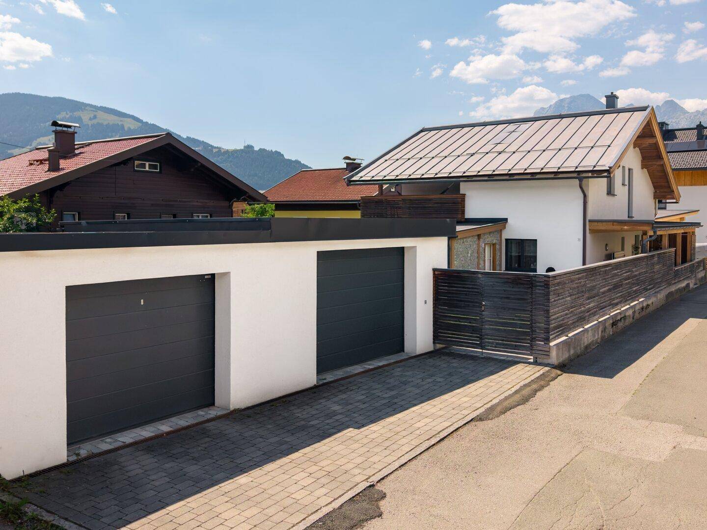 Doppelgarage mit Zufahrt und moderner Fassade des Hauses, gut integriert in die Umgebung.