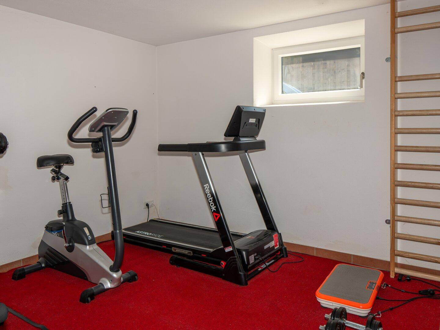 Fitnessraum im Untergeschoss mit Laufband und Heimtrainer, ideal für das tägliche Training.