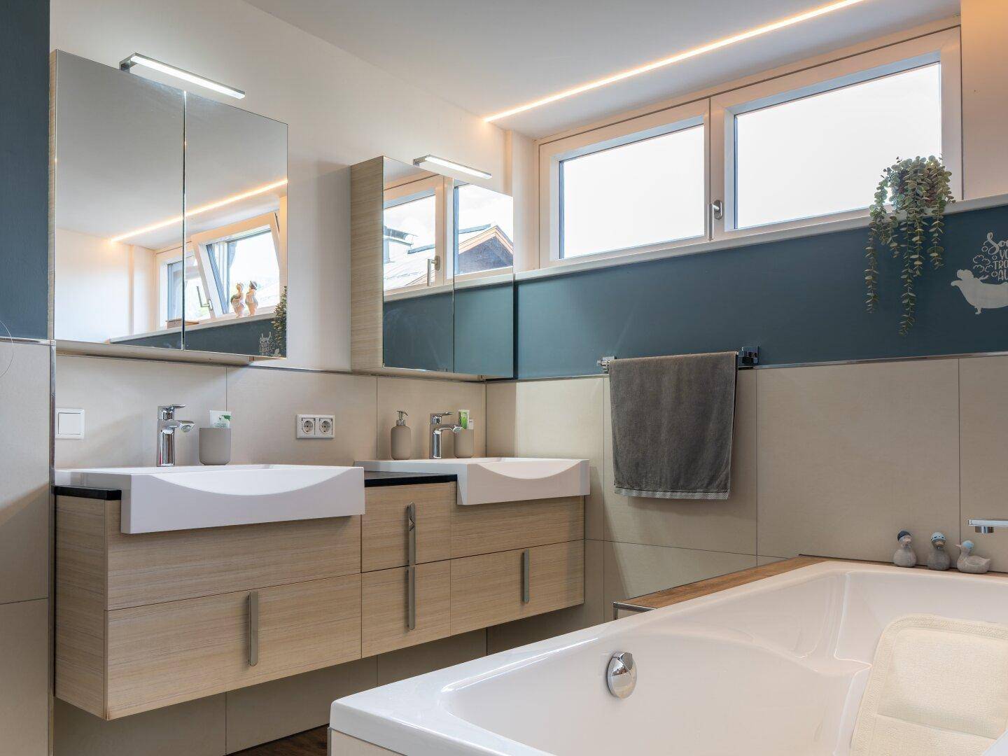 Modernes Badezimmer mit Doppelwaschbecken, Badewanne und großen Fenstern, hell und funktional.