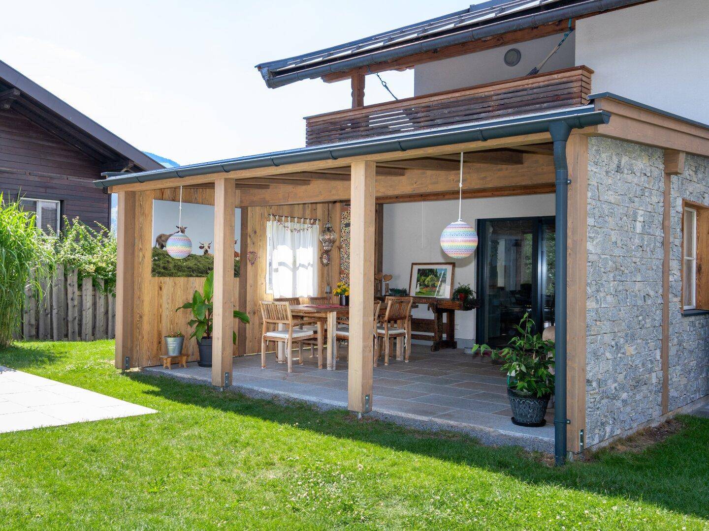 Geräumige überdachte Terrasse mit Holzbalken und Sitzgelegenheiten, ideal für Mahlzeiten im Freien.