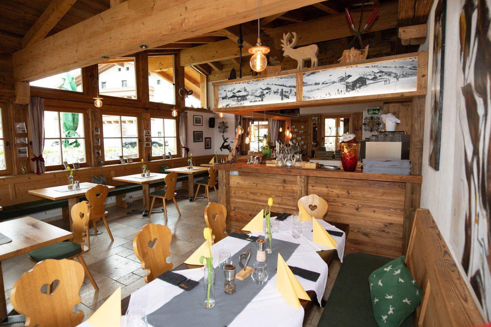 Gemütlicher Speisesaal im alpinen Stil mit Holzbalken, traditionellen Möbeln und Bar.
