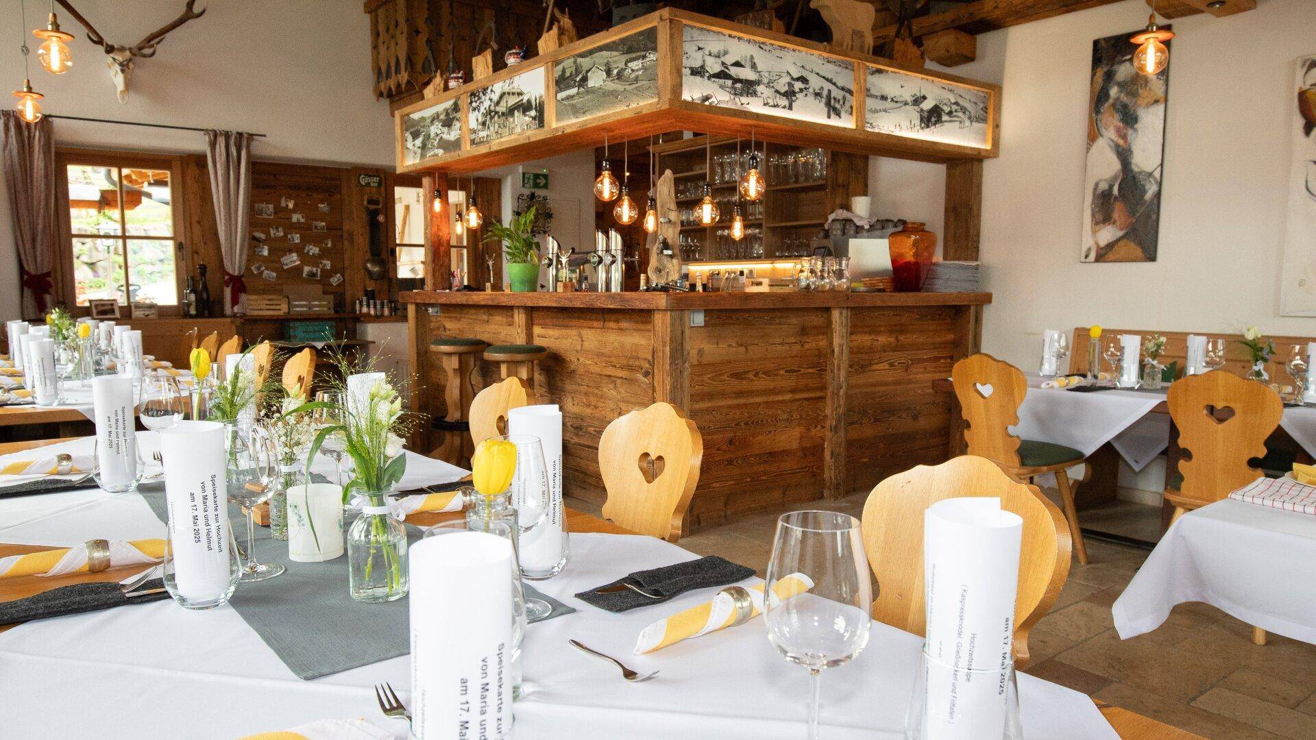 Rustikaler Essbereich mit Holztischen, Stühlen und einer einladenden Bar, bereit für Gäste.