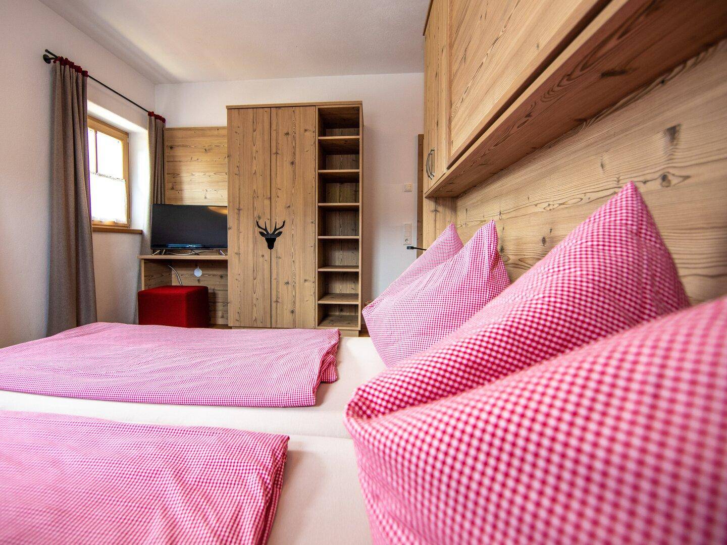 Gemütliches Schlafzimmer mit Holzeinrichtung, karierter Bettwäsche und Fernseher.