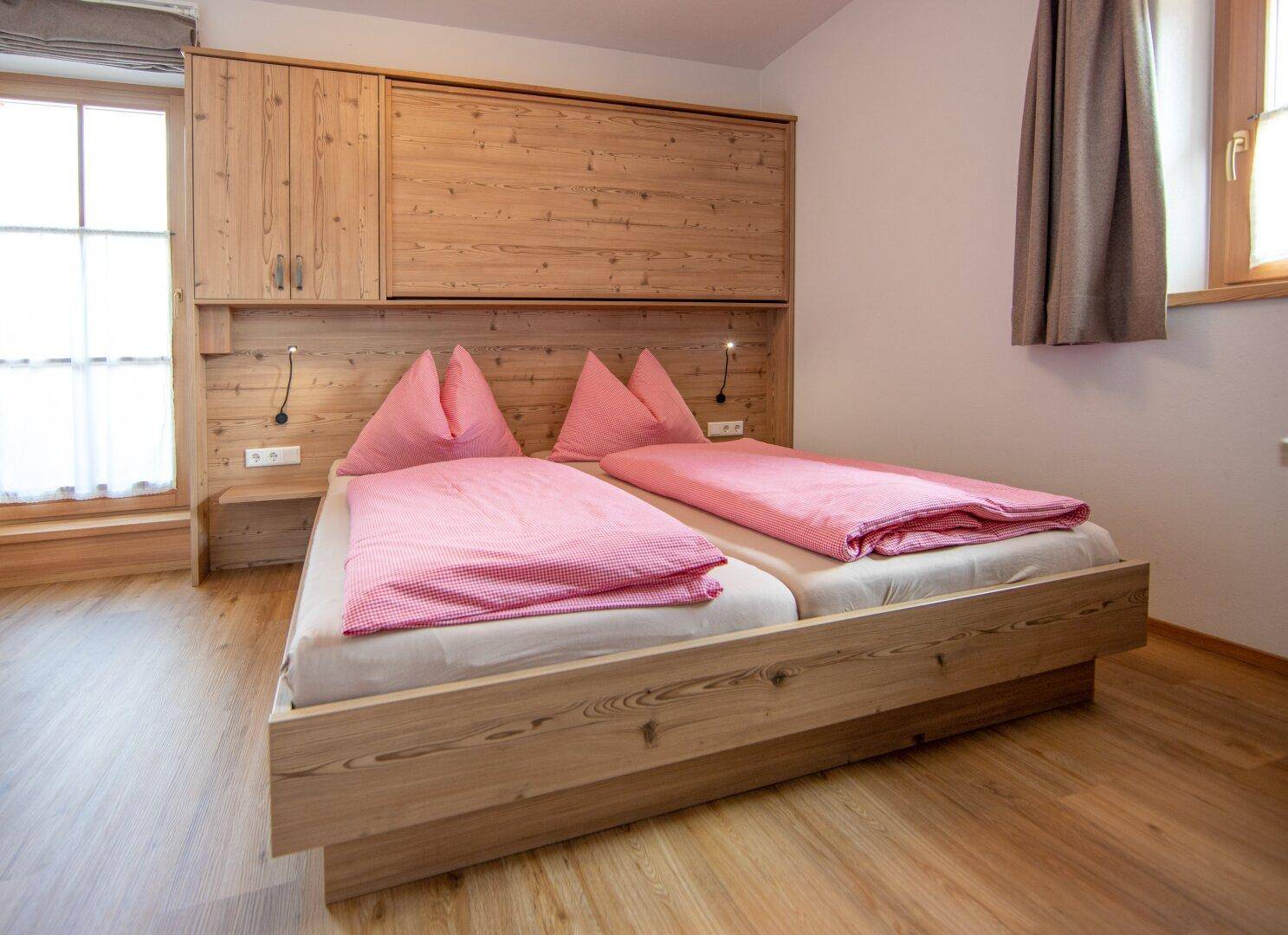 Helles Schlafzimmer mit zwei Einzelbetten, Holzeinrichtung und integrierten Nachttischen.