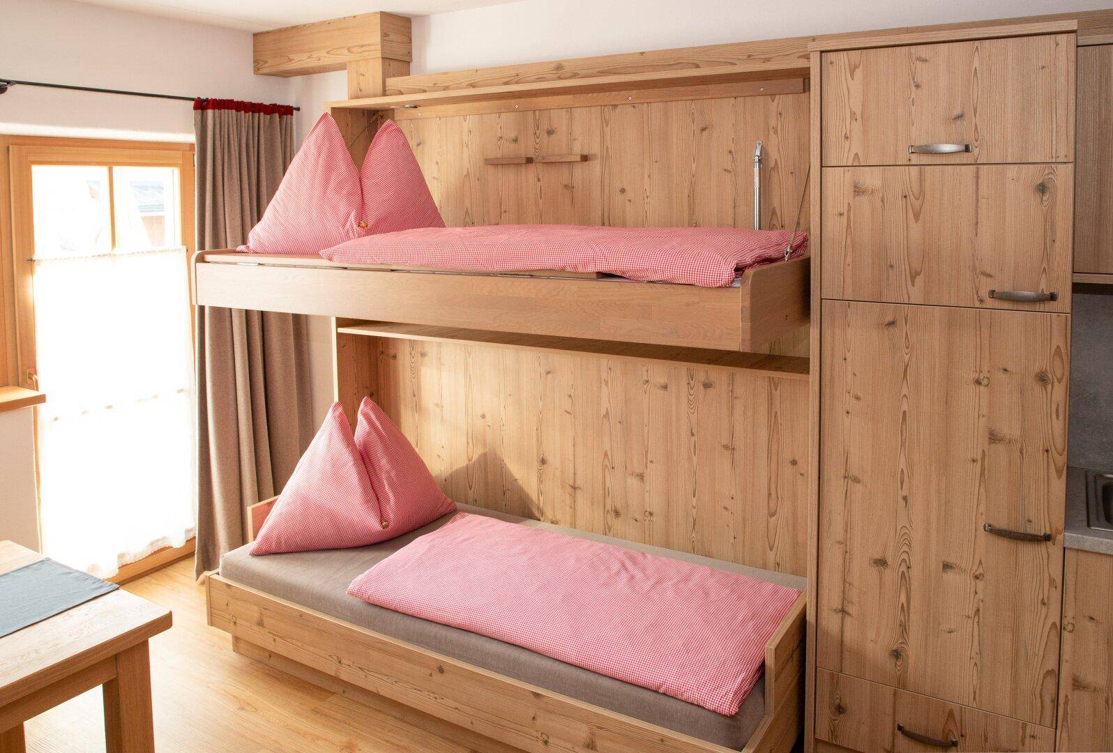 Schlafzimmer mit Etagenbetten aus Holz und integrierten Schränken, ideal für Kinder oder Gäste.