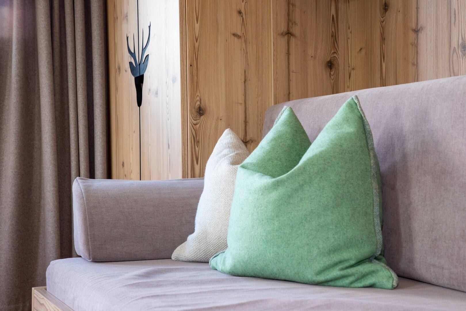 Nahaufnahme einer beigen Couch mit grünen und weißen Kissen, stilvoll dekoriert.