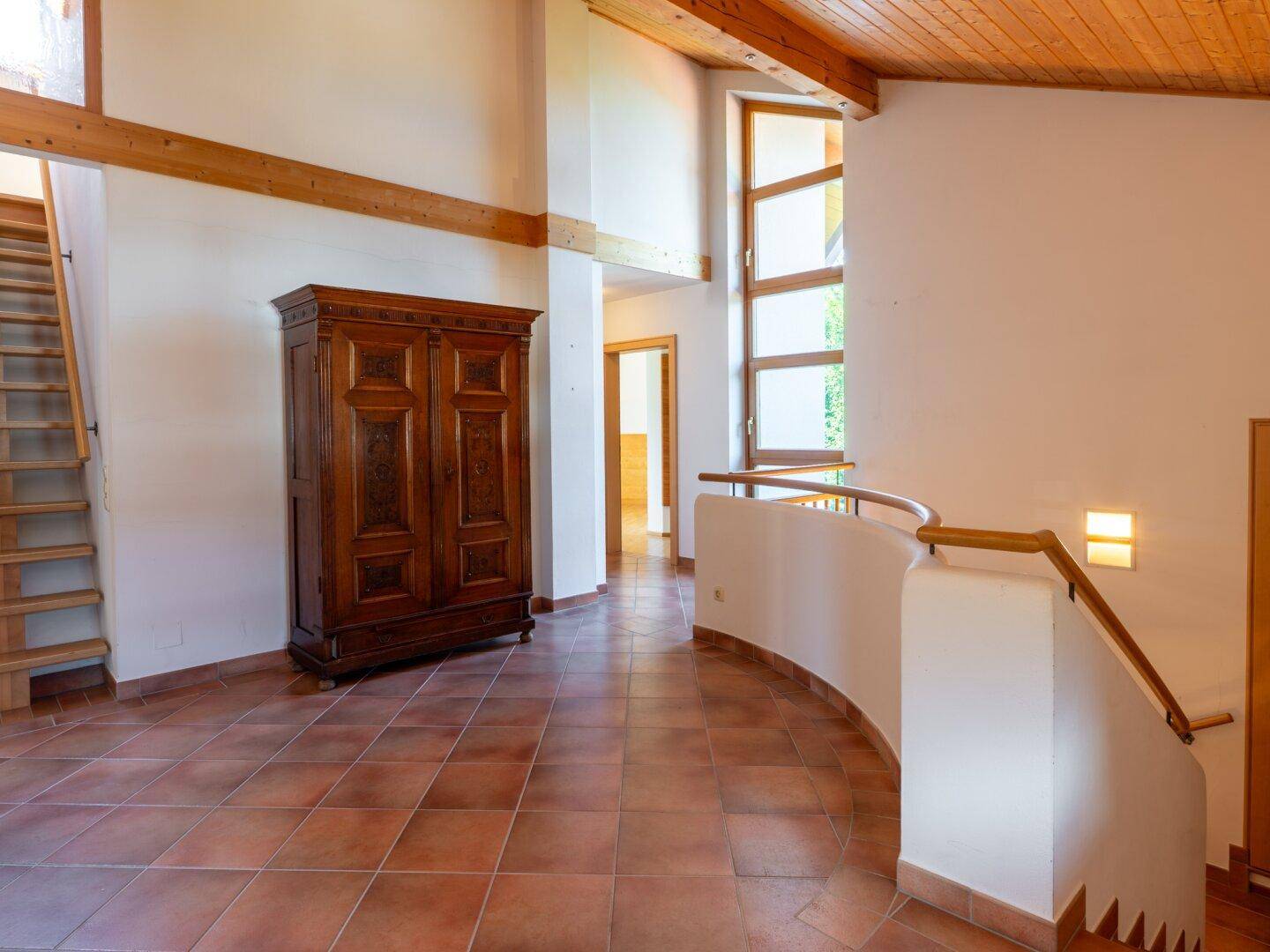 Geräumiger Flur mit hohen Decken, Holzbalken und Terrakottafliesen im Landhausstil.