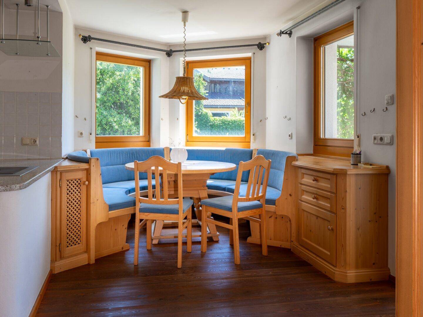 Traditionelle Wohnküche mit Eckbank, Holzelementen und Fenstern mit Blick ins Grüne.