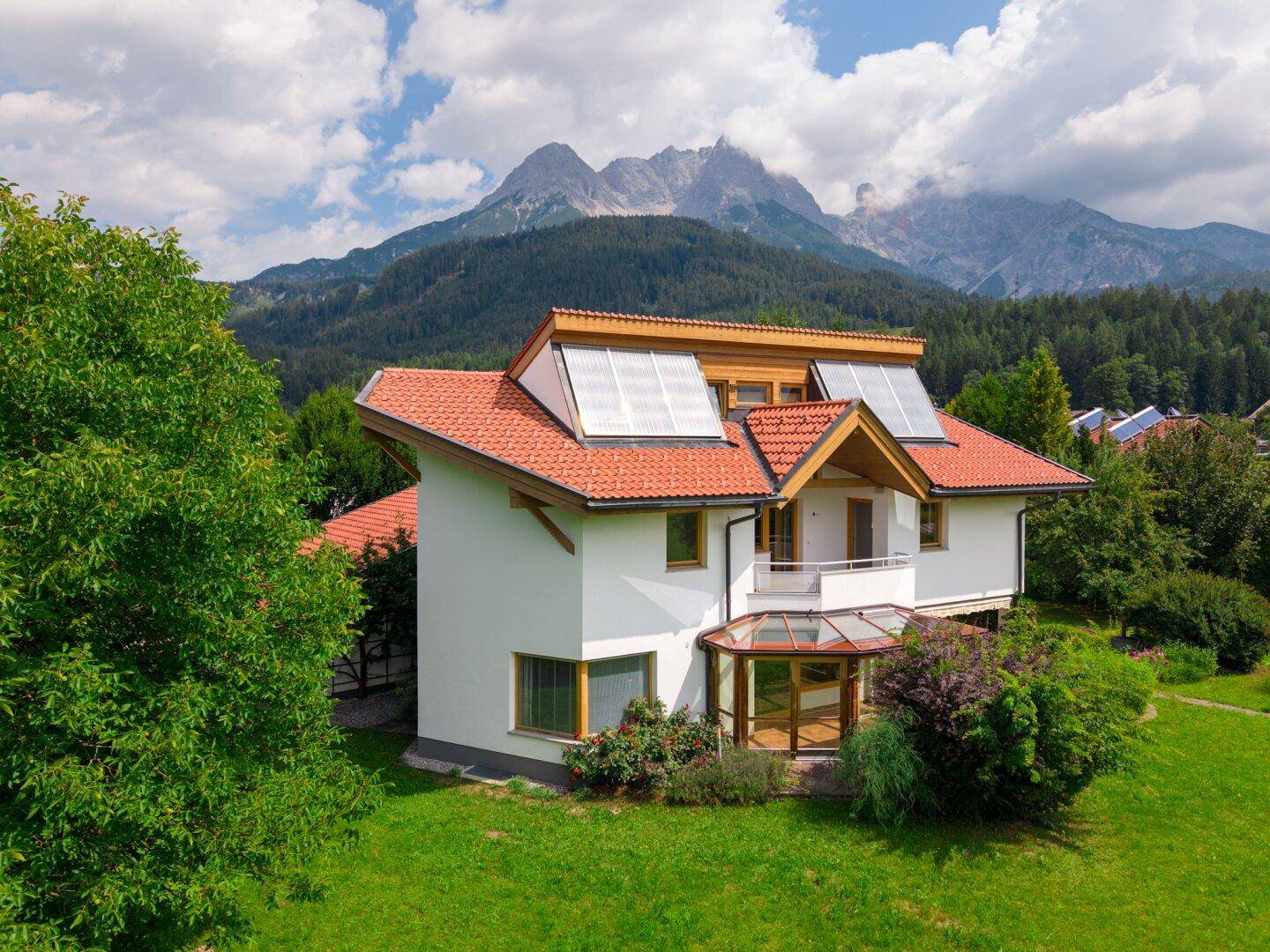 Freistehendes Haus mit Solarpaneelen auf dem Dach und beeindruckendem Alpenpanorama.