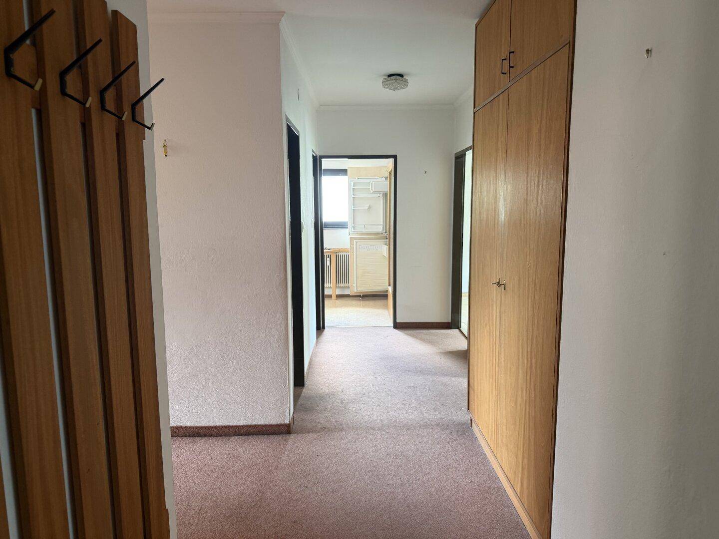 Flur mit praktischen Einbauschränken aus Holz und einer Garderobe, der zu den Zimmern führt.