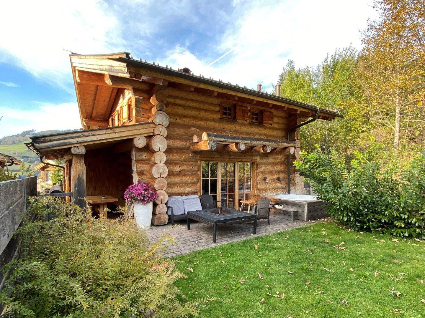 Gartenbereich mit Terrasse, Sitzgelegenheiten und einem Whirlpool neben dem Holzhaus.