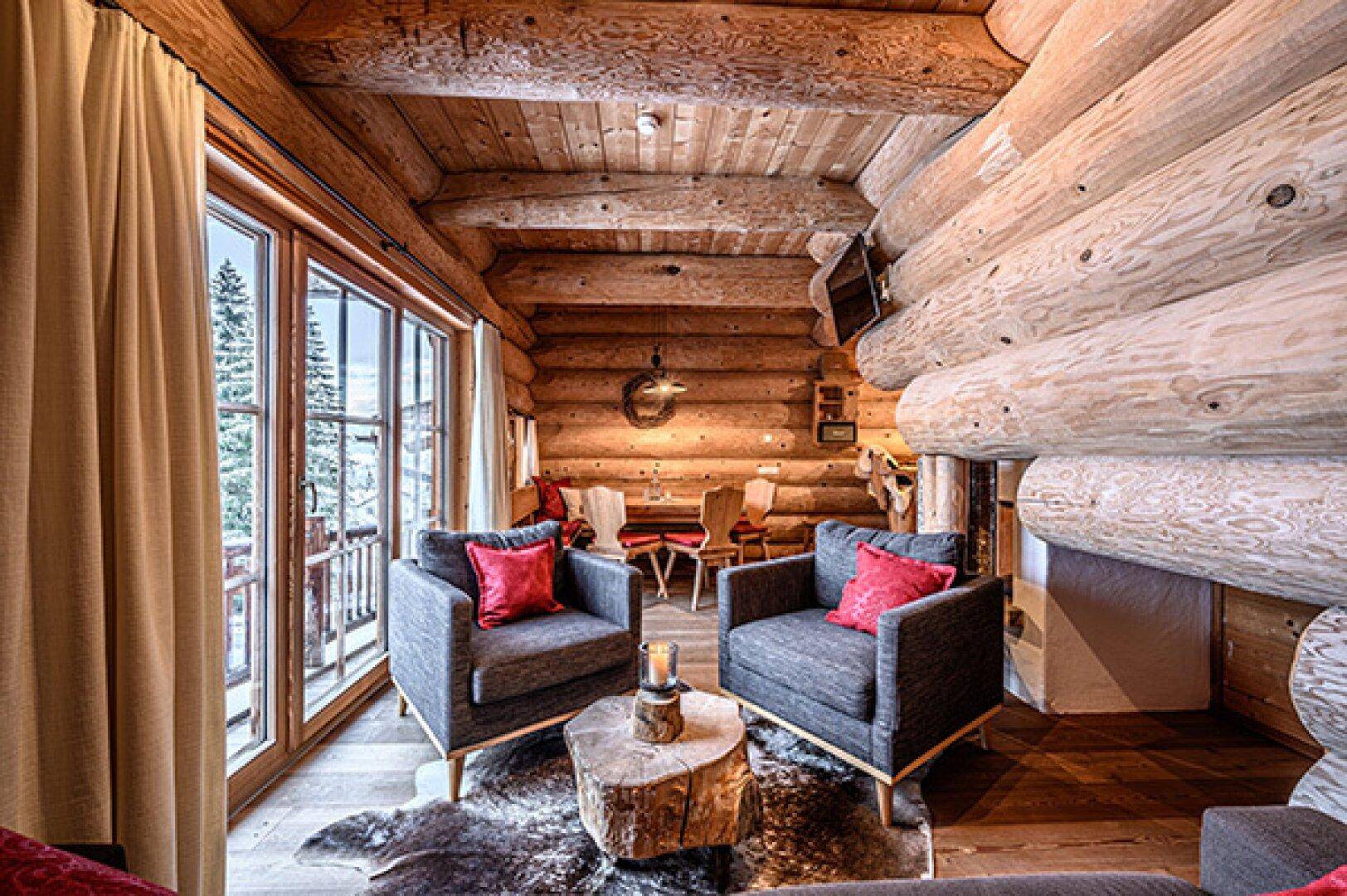 Gemütlicher Wohn- und Essbereich in einem Holzhaus mit großen Fenstern und Bergblick.