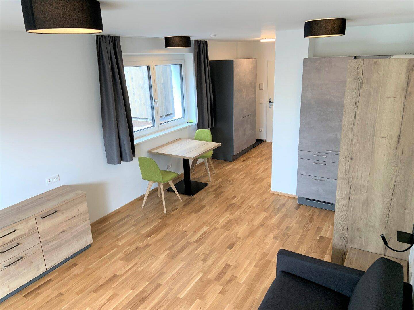 Heller Wohnbereich mit Holzboden, kleinem Esstisch und Sofa, ideal für gemütliche Stunden.