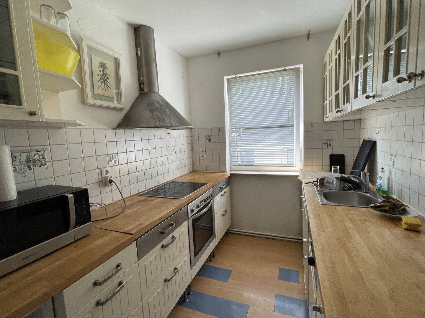 Funktionale Küche mit Holz-Arbeitsplatten, weißen Schränken und integrierten Geräten.