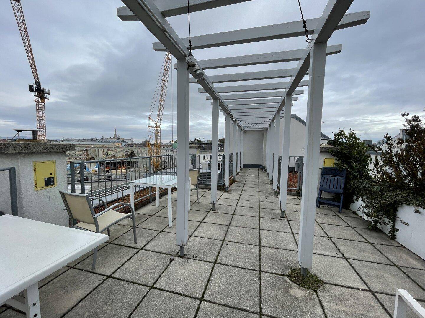 Weitläufige Dachterrasse mit Pergola und Panoramablick über die Stadt, perfekt für Outdoor-Aktivitäten.