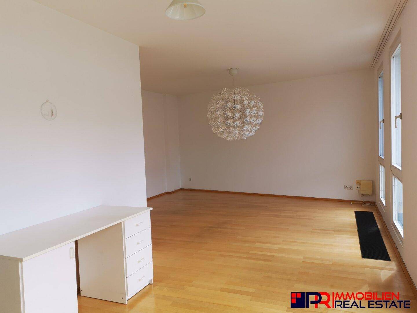 Heller und geräumiger Wohnbereich mit Parkettboden und großen Fenstern, bietet viel Tageslicht.