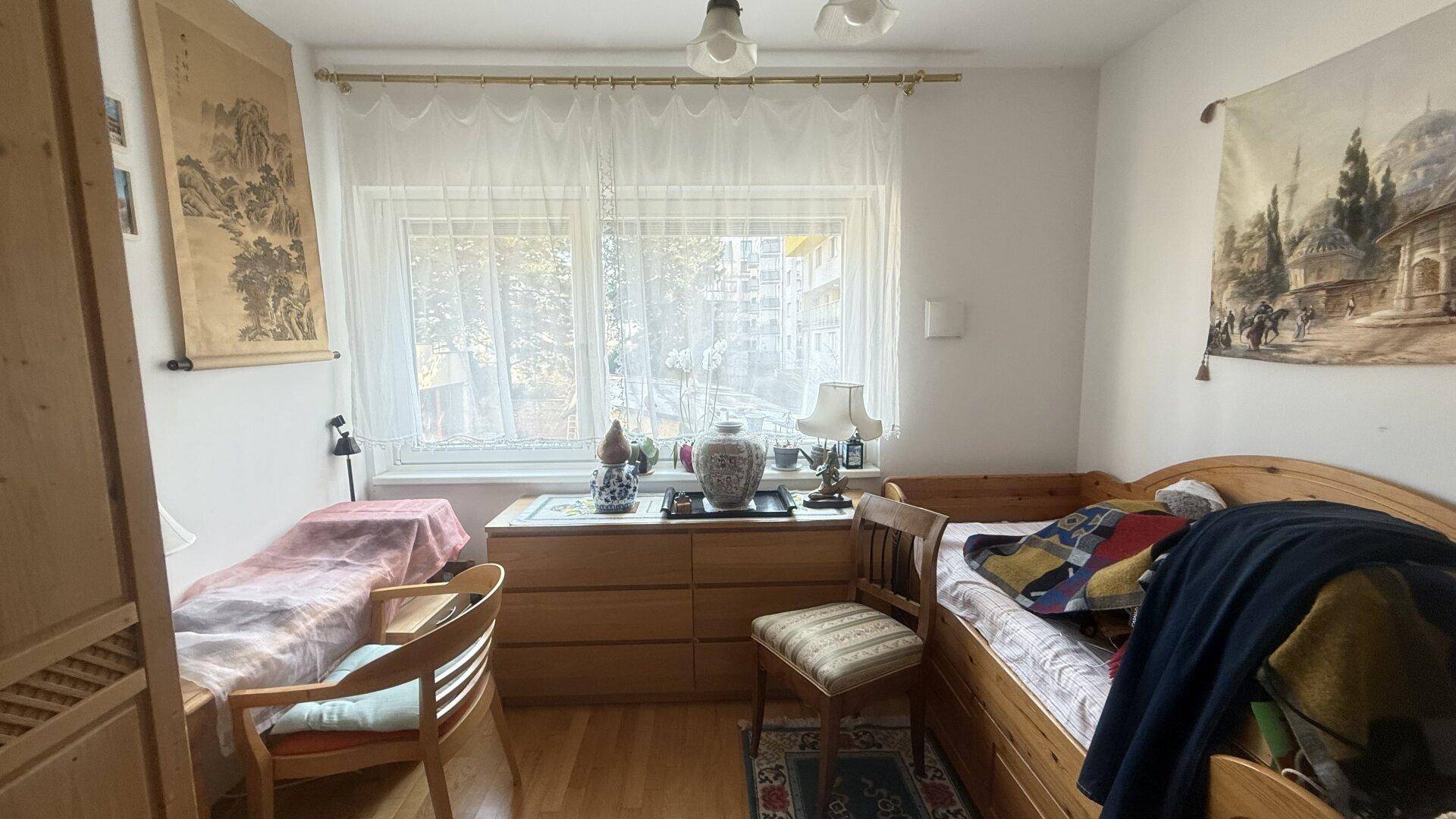 Gemütliches Schlafzimmer mit Holzboden, Fenster und traditioneller Einrichtung.