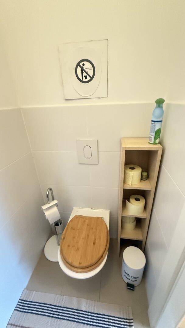 Gäste-WC mit Toilette und kleinem Regal.