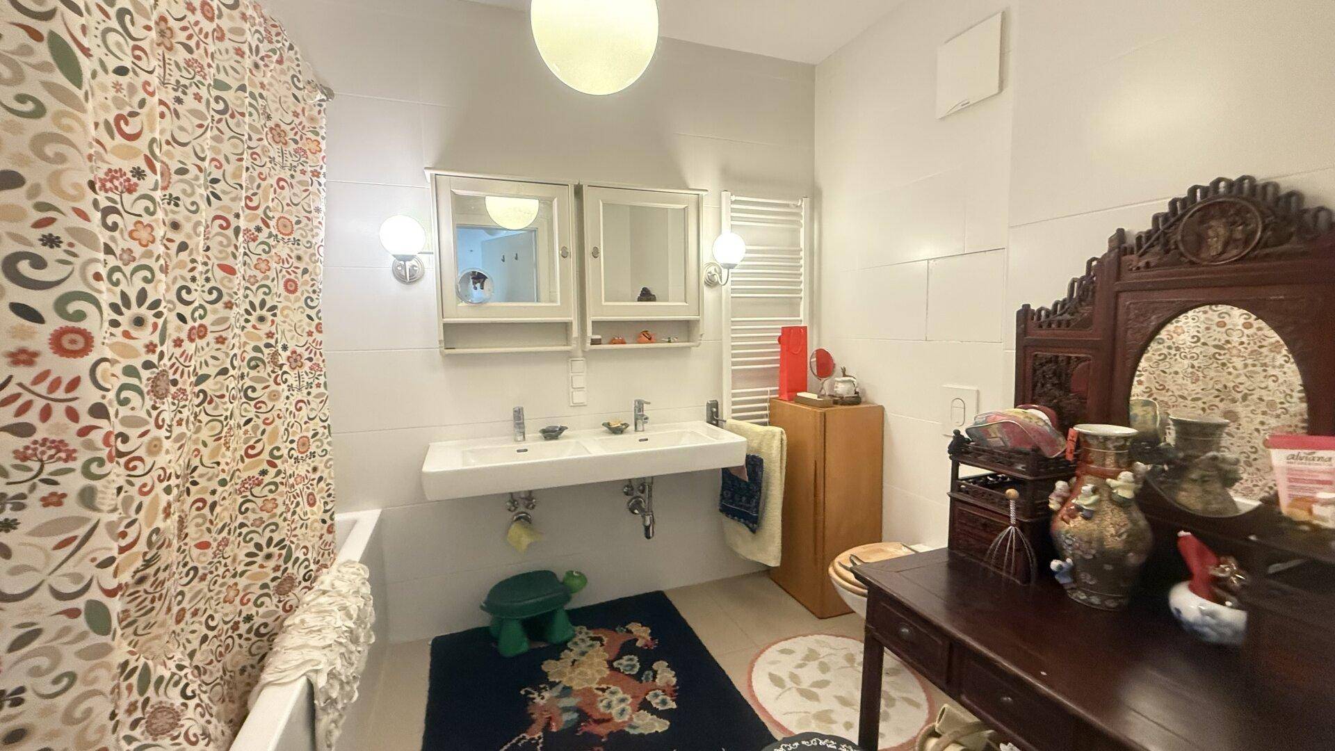Geräumiges Badezimmer mit Doppelwaschbecken, Badewanne und dekorativem Spiegel.