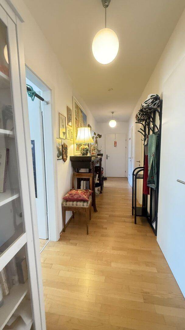 Langer Flur mit Holzboden, Garderobe und heller Beleuchtung.