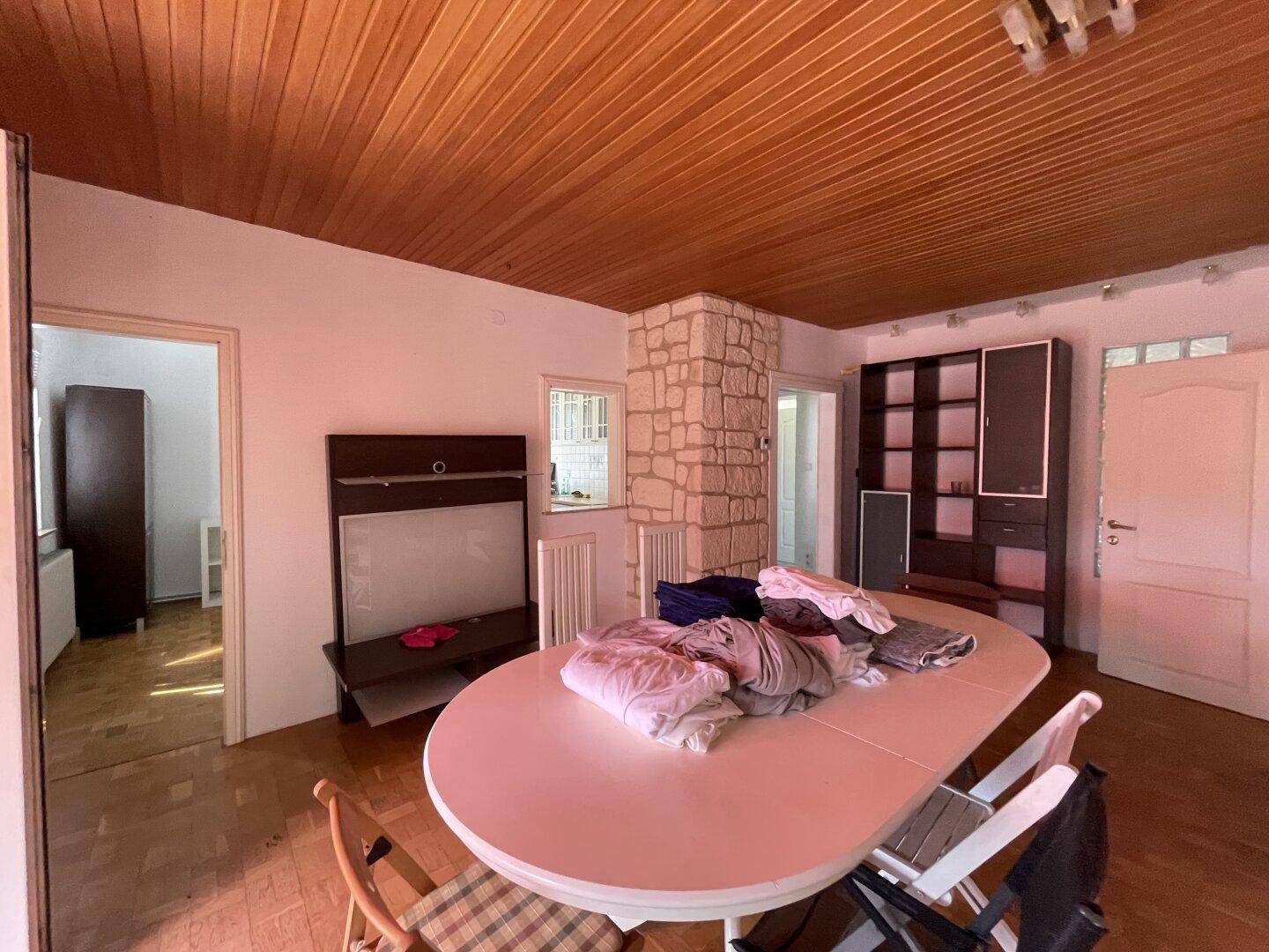 Esszimmer mit Holzboden, Holzdecke und großem Esstisch, angrenzend an weitere Räume.