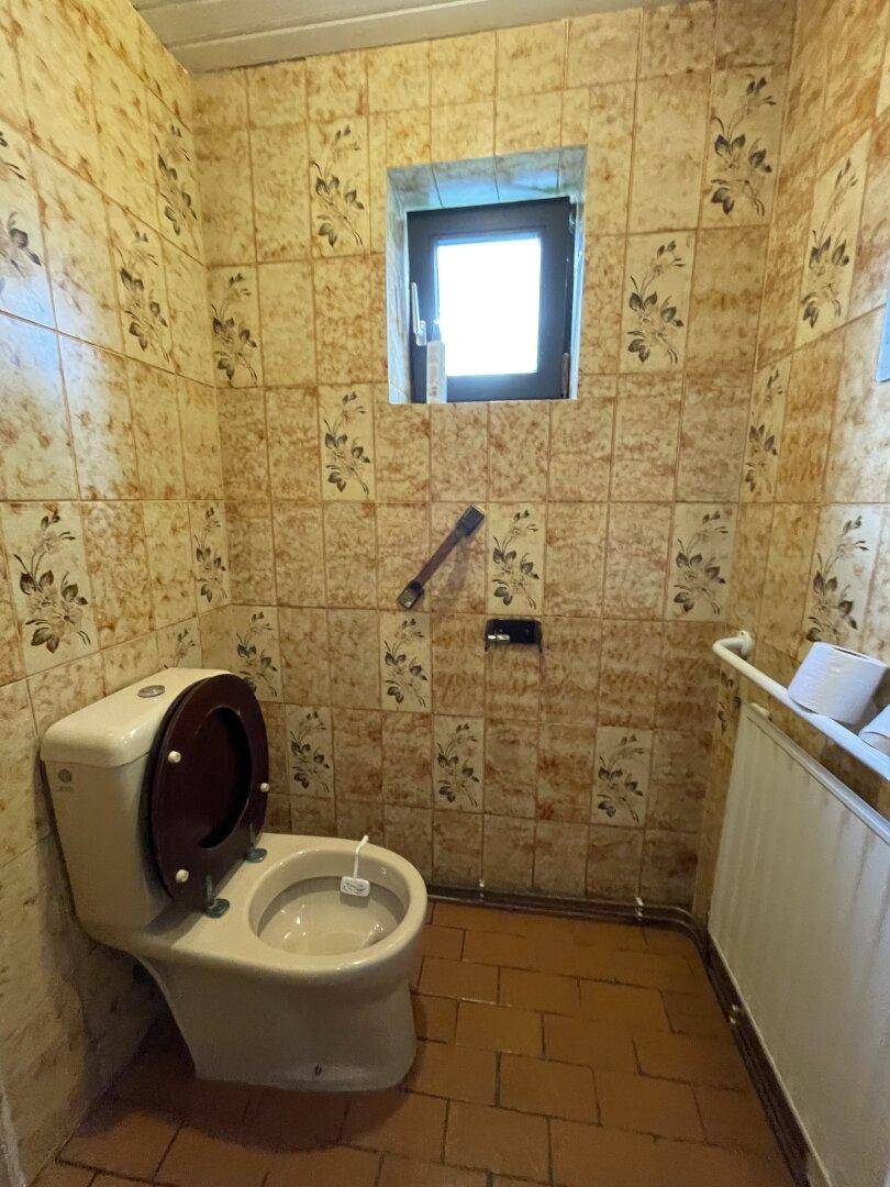 Separates WC mit gemusterten Fliesen und Fenster, im Stil der 80er Jahre.