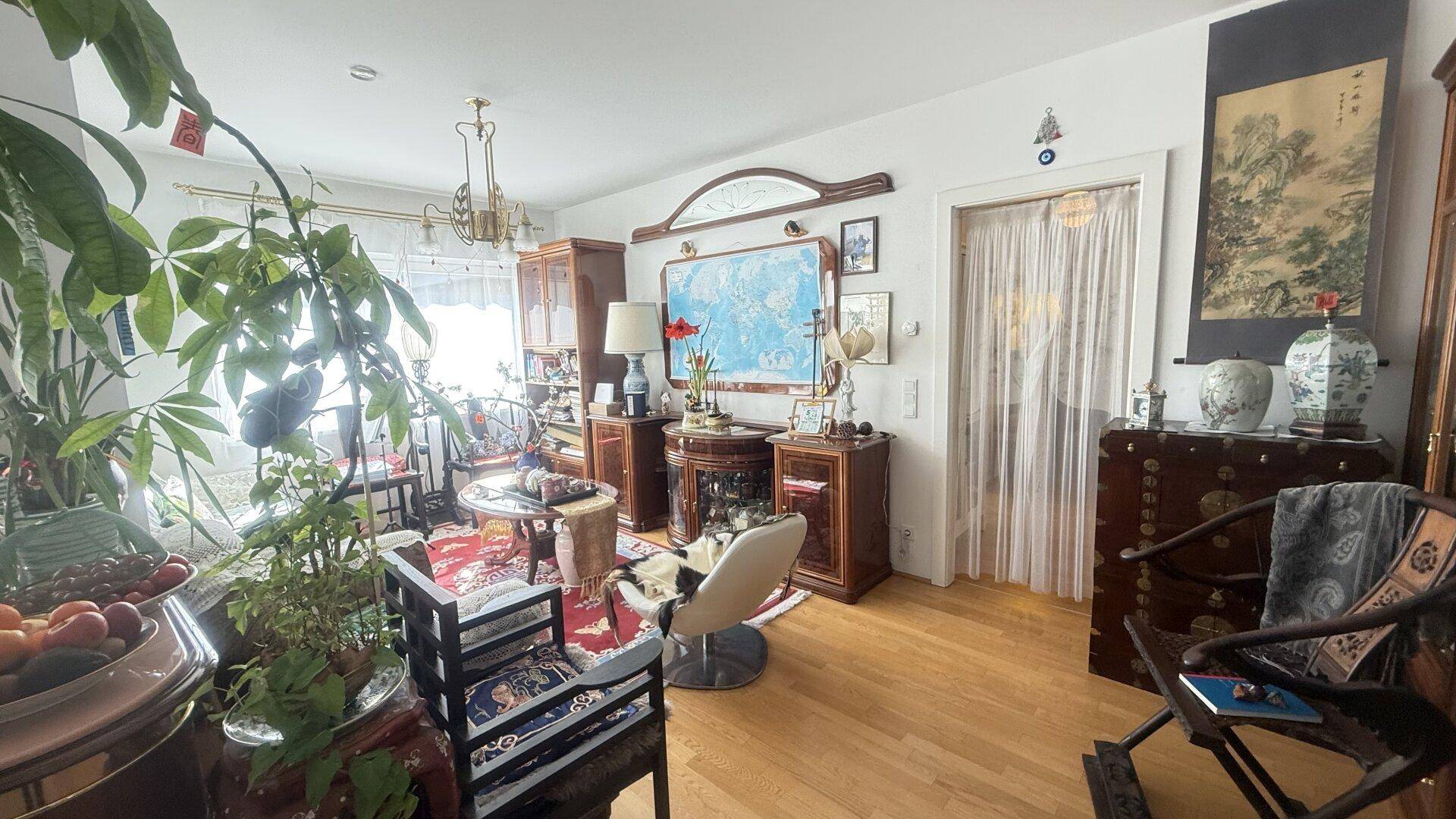 Wohnzimmer mit Holzboden, Pflanzen und traditionellen Dekorationselementen.