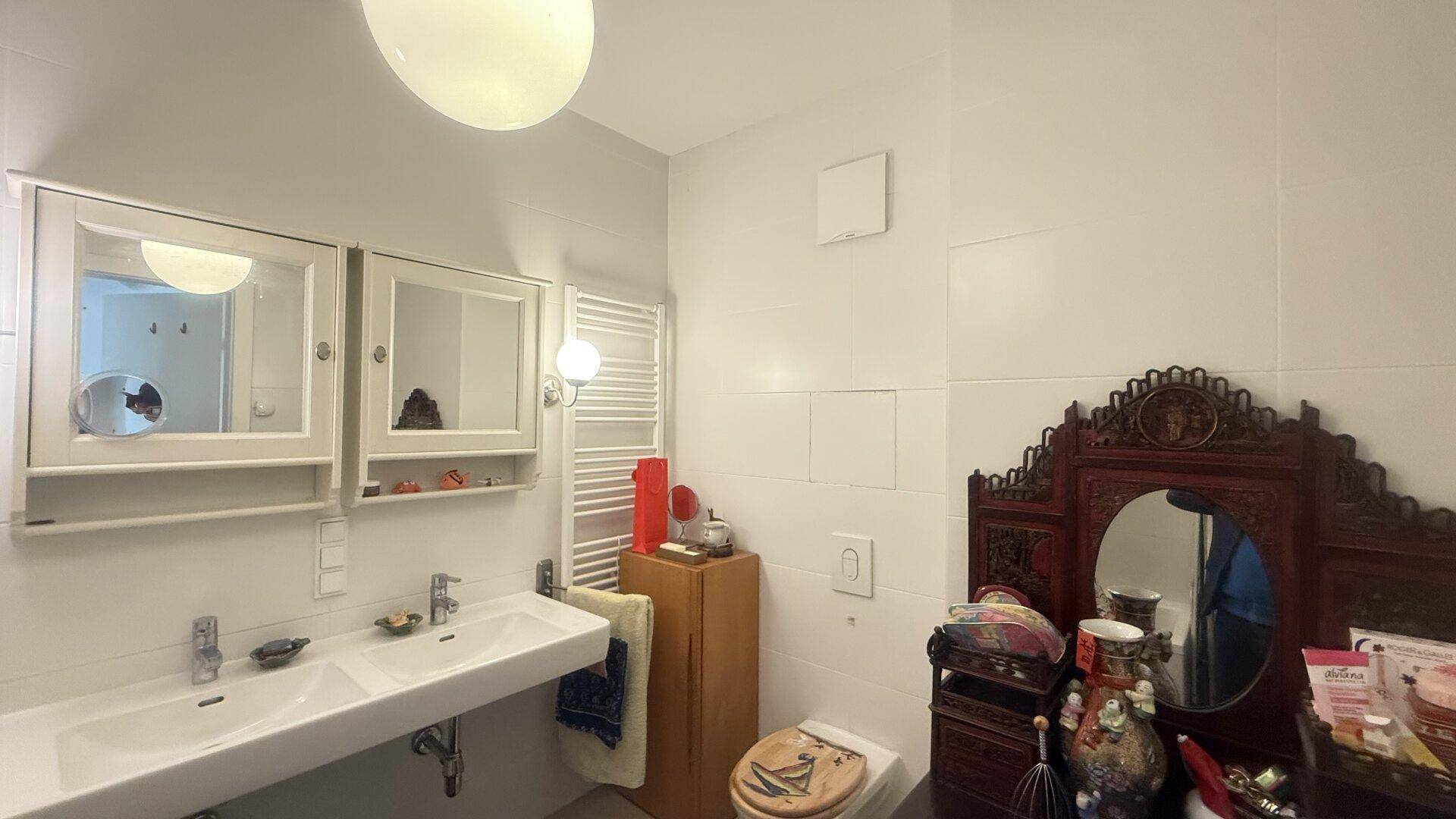 Badezimmer mit Doppelwaschbecken, Toilette und Spiegelschränken.