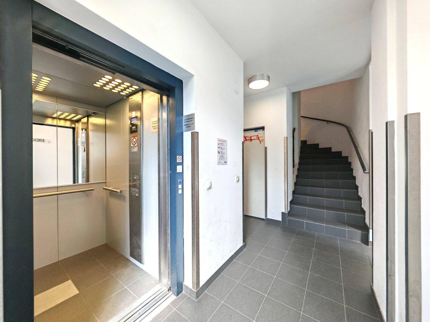 Heller Flur mit modernem Aufzug und Treppenhaus in einem Mehrfamilienhaus.
