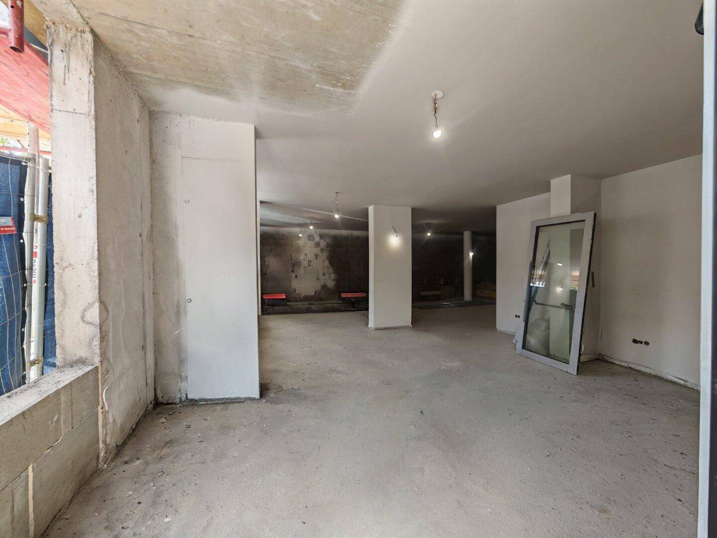 Unfertiger Raum mit Betonstruktur und großen Fensteröffnungen, im Rohbauzustand.