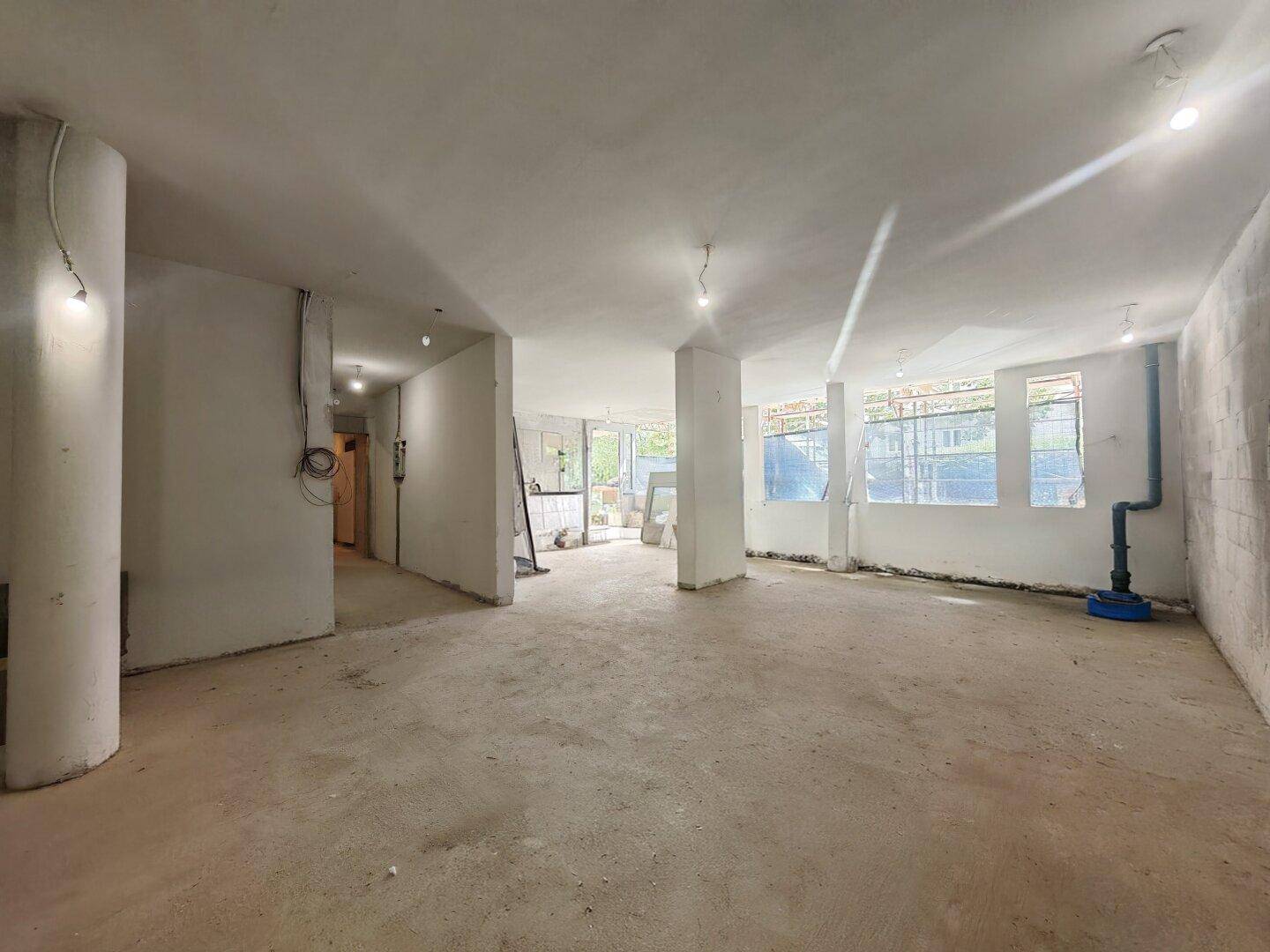 Großer, unfertiger Innenraum mit Betonboden und sichtbaren Säulen, bereit für den Innenausbau.
