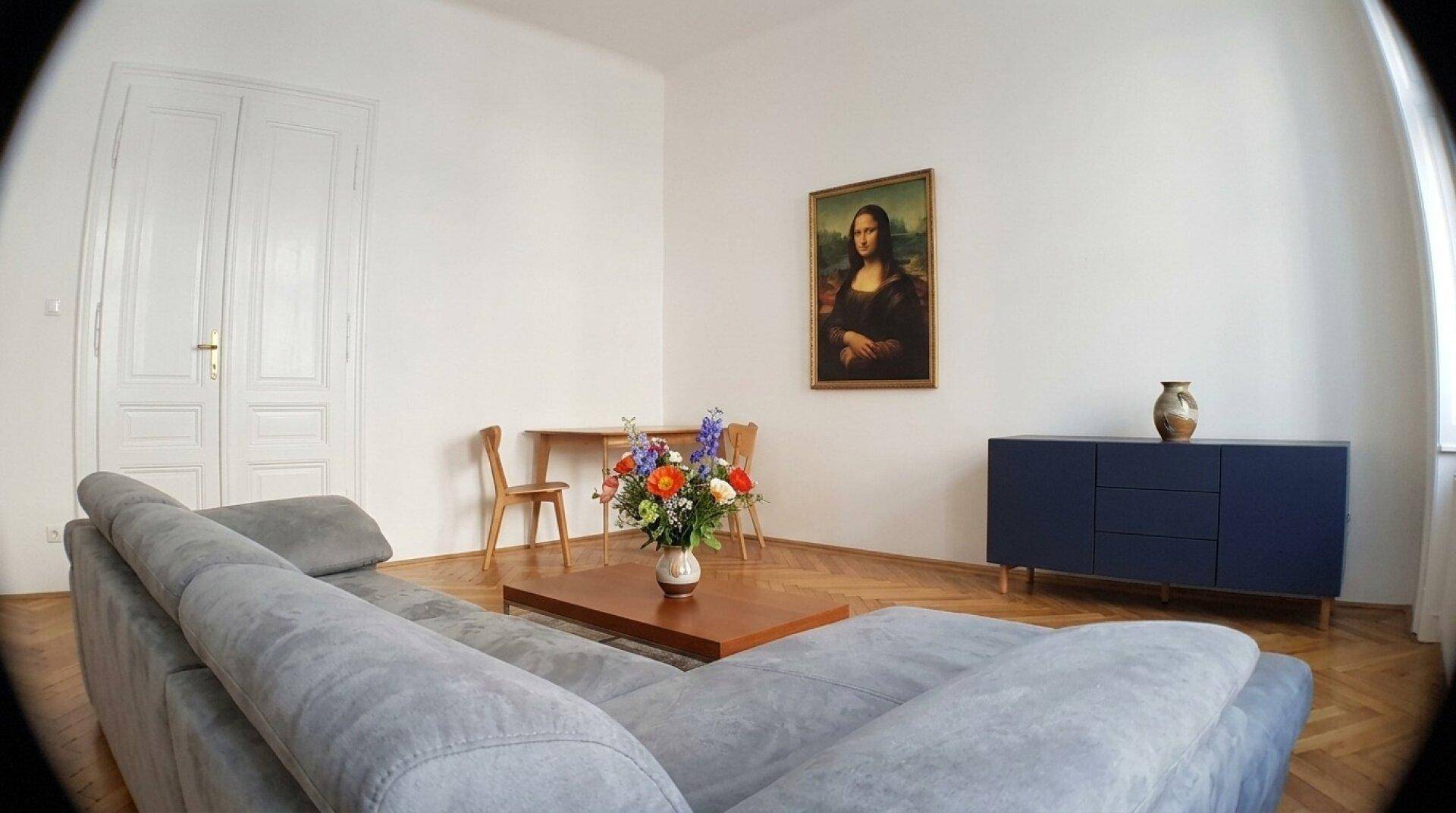 Gemütlicher Wohn- und Essbereich mit Fischgrätparkett, eleganten Doppeltüren und modernem Mobiliar.