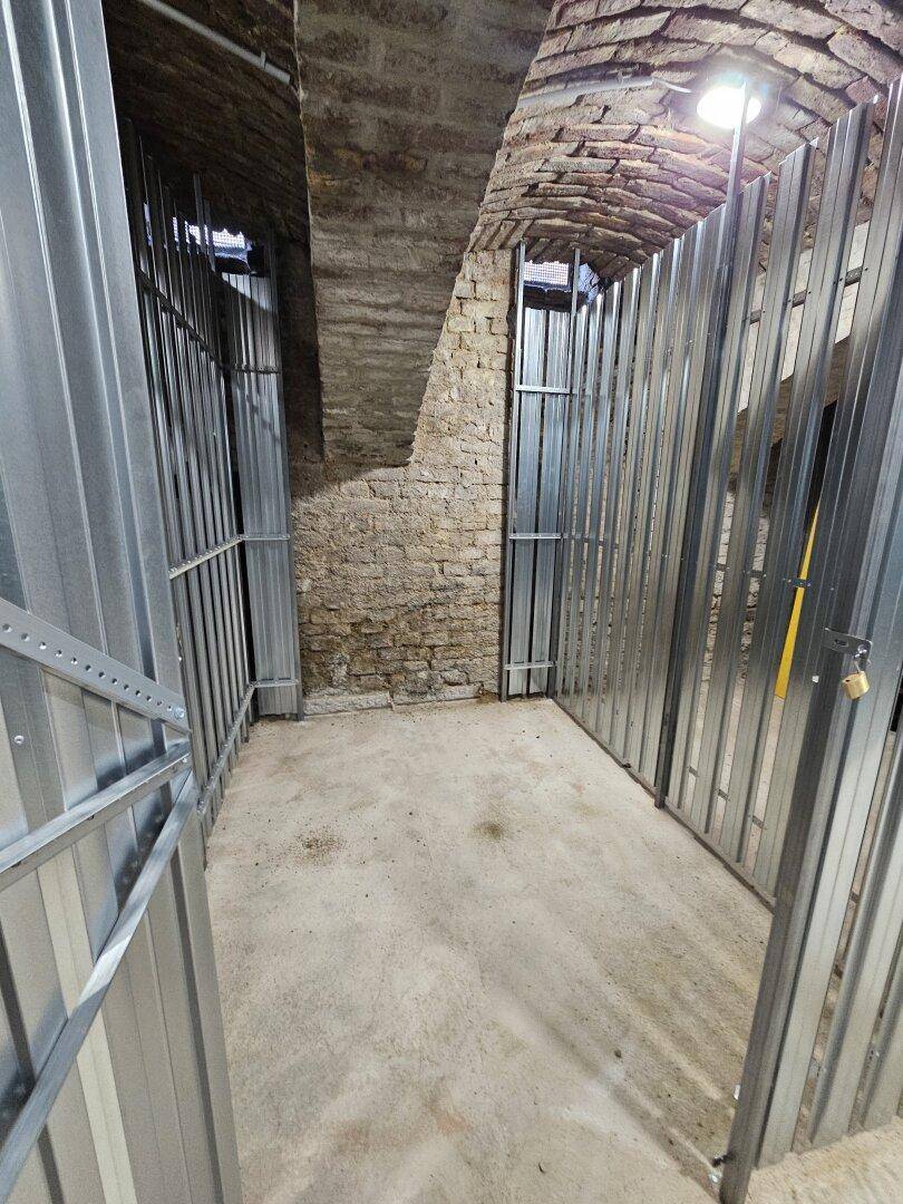 Kellerabteile mit robusten Metallgittern und historischen Gewölbedecken aus Ziegelstein.