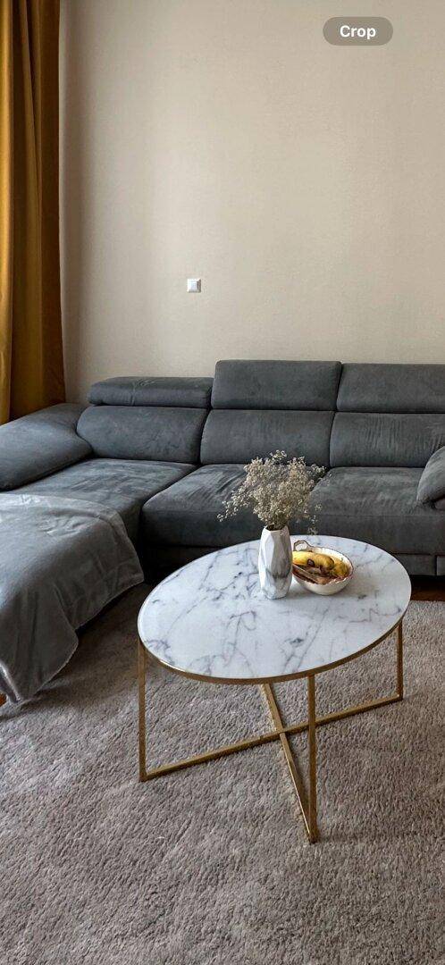 Gemütliches Ecksofa mit Couchtisch aus Marmor und Teppich im Wohnbereich.