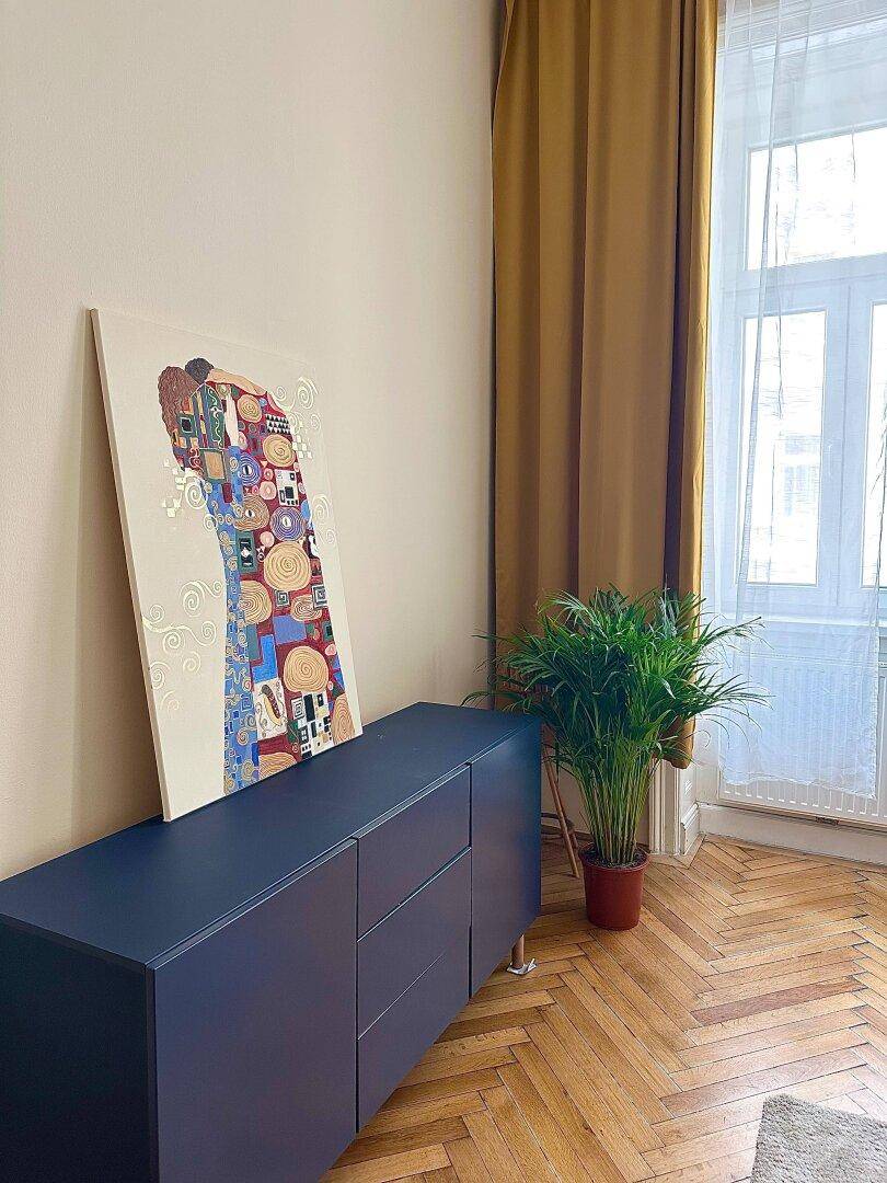 Detailansicht des Sideboards mit Kunstwerk und Grünpflanze im Wohnzimmer.