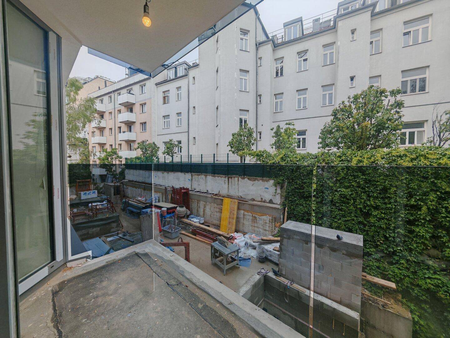 Blick von einem im Bau befindlichen Balkon auf die Baustelle und die umliegenden Häuser.