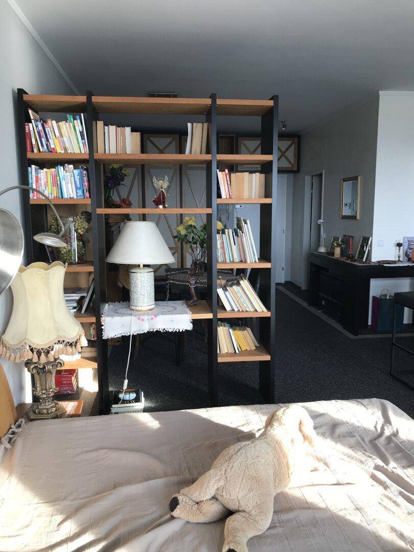Detailansicht eines Bücherregals neben dem Bett, mit dekorativer Lampe und Büchern.