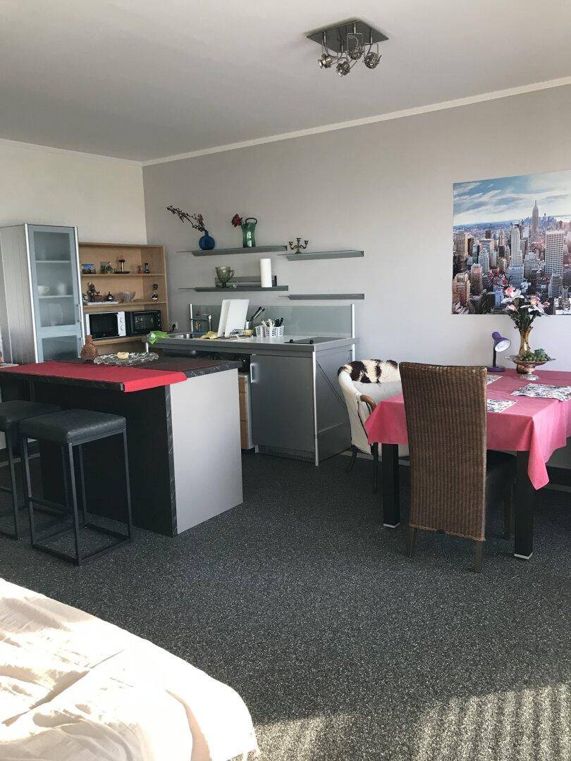 Kleine Küchenzeile mit Essbereich und moderner Einrichtung in einem offenen Wohnraum.