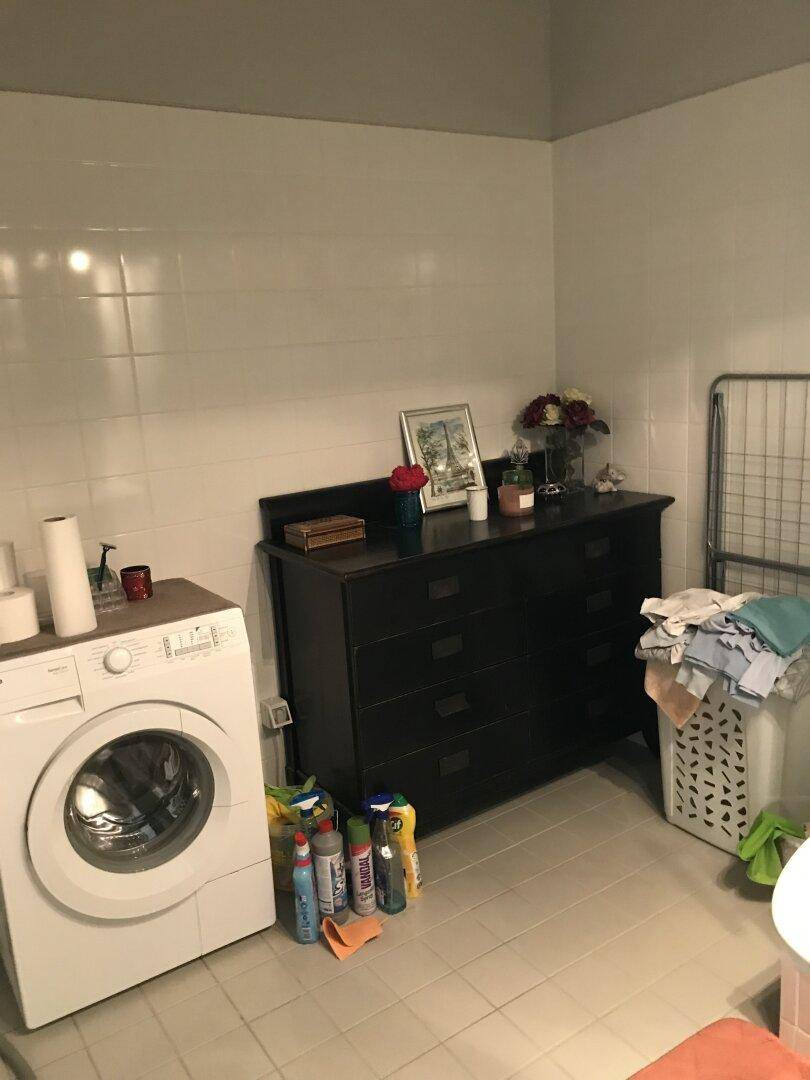 Waschküche mit Waschmaschine, Kommode und Fliesenboden, ideal für den Haushalt.