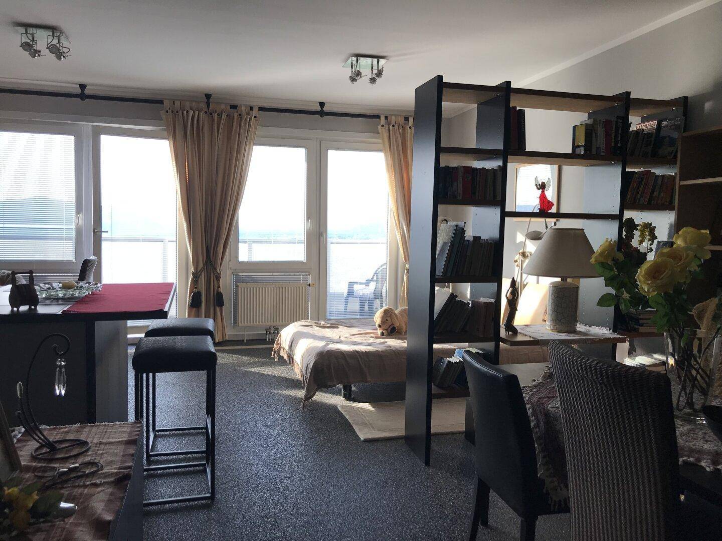 Offener Wohnbereich mit Schlafgelegenheit, Essbereich und großen Fenstern mit Weitblick.