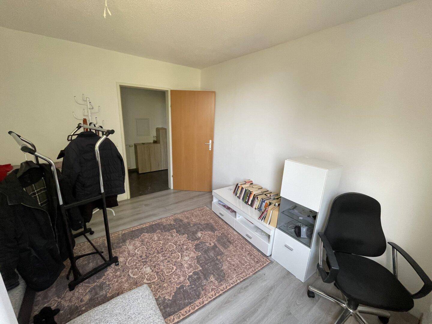 Arbeitszimmer mit Schreibtischstuhl, Regal und Blick auf den Flur.