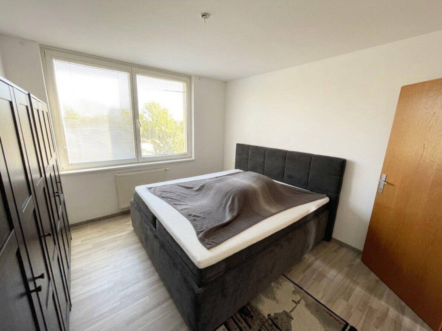 Schlafzimmer mit Doppelbett, großem Kleiderschrank und hellem Laminatboden.